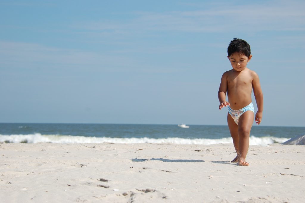 Para ilustra o desfralde, imagem de menino na praia com fraldas