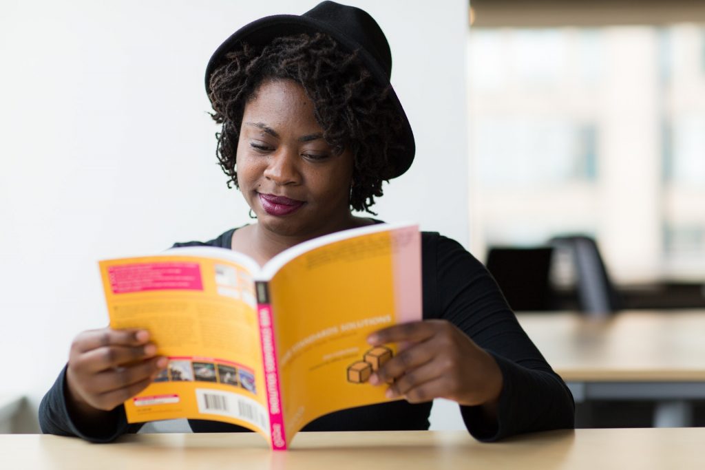 Mulher negra lendo um livro para ilustrar o post sobre como escrever um livro