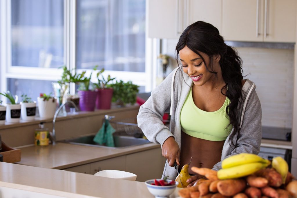 Mulher negra cortando uma pera na cozinha