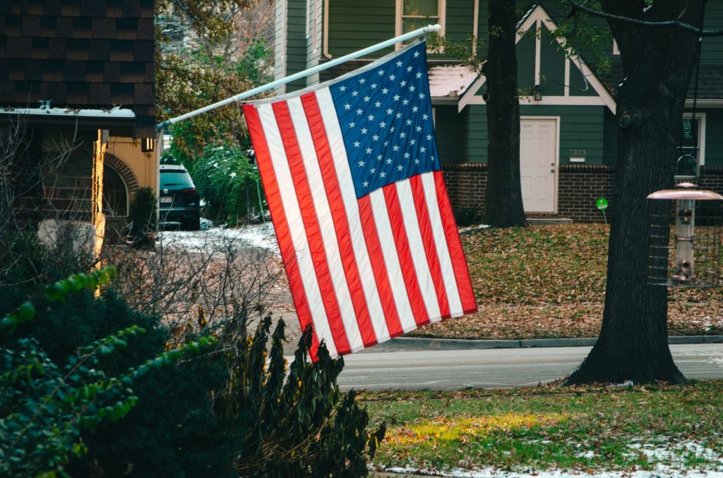 Foto da bandeira do Estados Unidos pendurada em frente a uma casa.