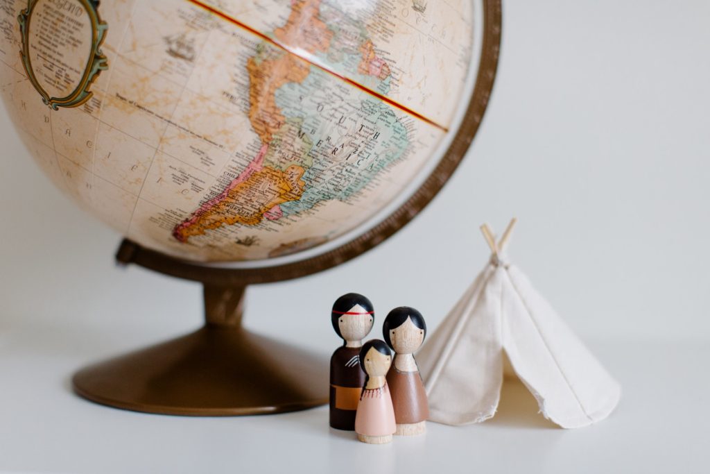 Imagem com itens de decoração: globo do mundo, três miniaturas e uma cabaninha pequena.