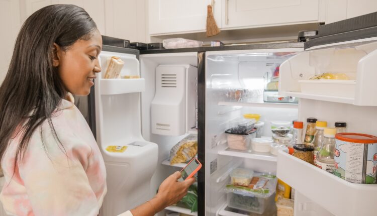 mulher negra em frente a uma geladeira organizada